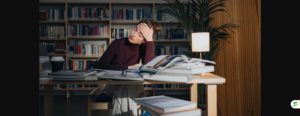Exhausted student resting head on hand while studying in a library