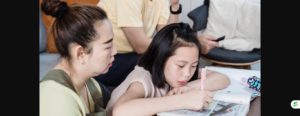 Mother watching her daughter do homework at the table