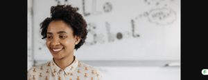 Smiling teacher standing calmly in front of a classroom whiteboard