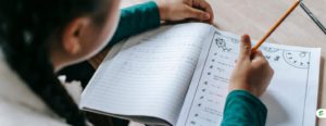 Student completing a math worksheet in a notebook during a homework session