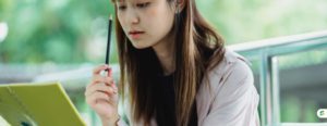 Student pausing to recall information from memory while studying with a notebook
