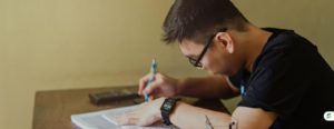 Student writing notes at a desk while studying for a test