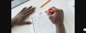 Teacher marking a test paper with a red pen