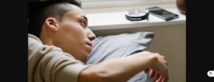 Teenage boy checking a smartwatch and phone after waking up